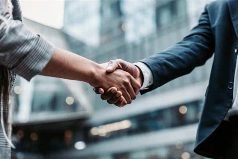 Two businesspeople shaking hands after finalising a complex corporate finance deal involving trusts, LLPs, or SPVs.