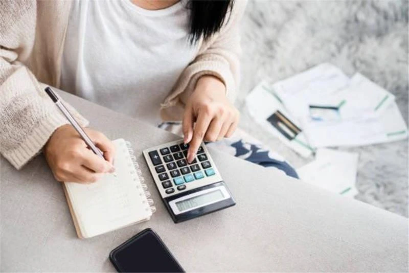 Property developer calculating refinance figures with calculator and paperwork