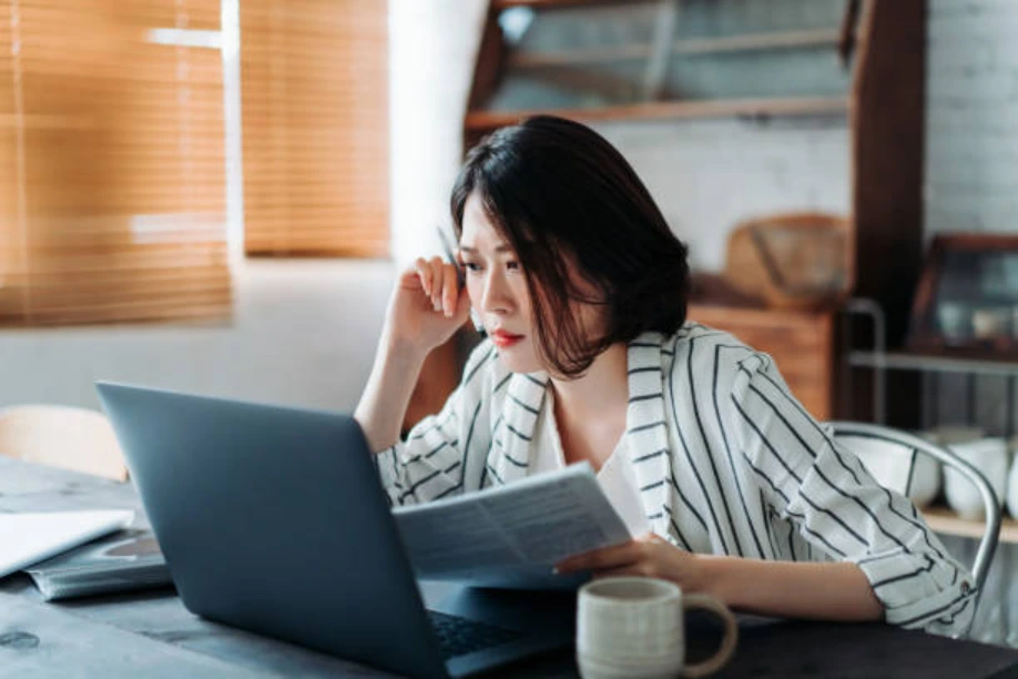 Business owner reviewing financial documents while analysing commercial mortgage stress test figures on a laptop