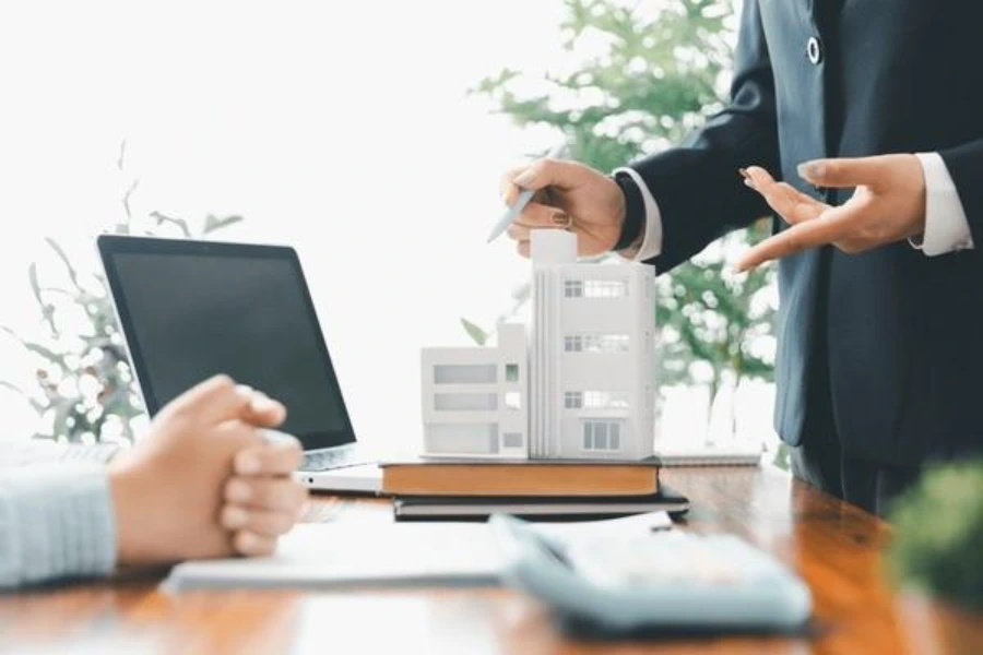 Advisor explaining commercial property finance options with a building model during a property investment meeting