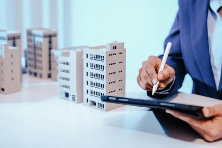 Property advisor reviewing commercial property finance options on a tablet beside model commercial buildings