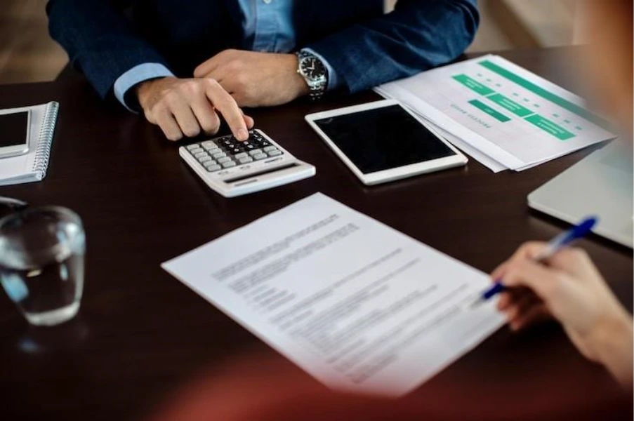 Commercial mortgage refinancing showing financial review with calculator and loan documents being assessed