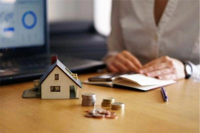 person planning HMO conversion funding with laptop coins and house model representing the two-stage bridging to term finance structure